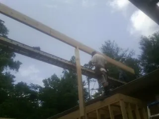 Carpenter setting a ridge beam over a new addition frame — Ice Dam Removal by Roofing Brothers in Goodspring