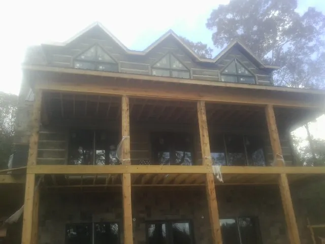 Dormers and porch framing on a large log home under construction — Roof Coating work by our crew in Goodspring