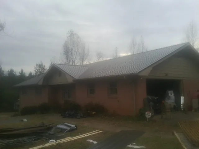 Gray metal roof on a stucco house with an attached garage in Goodspring