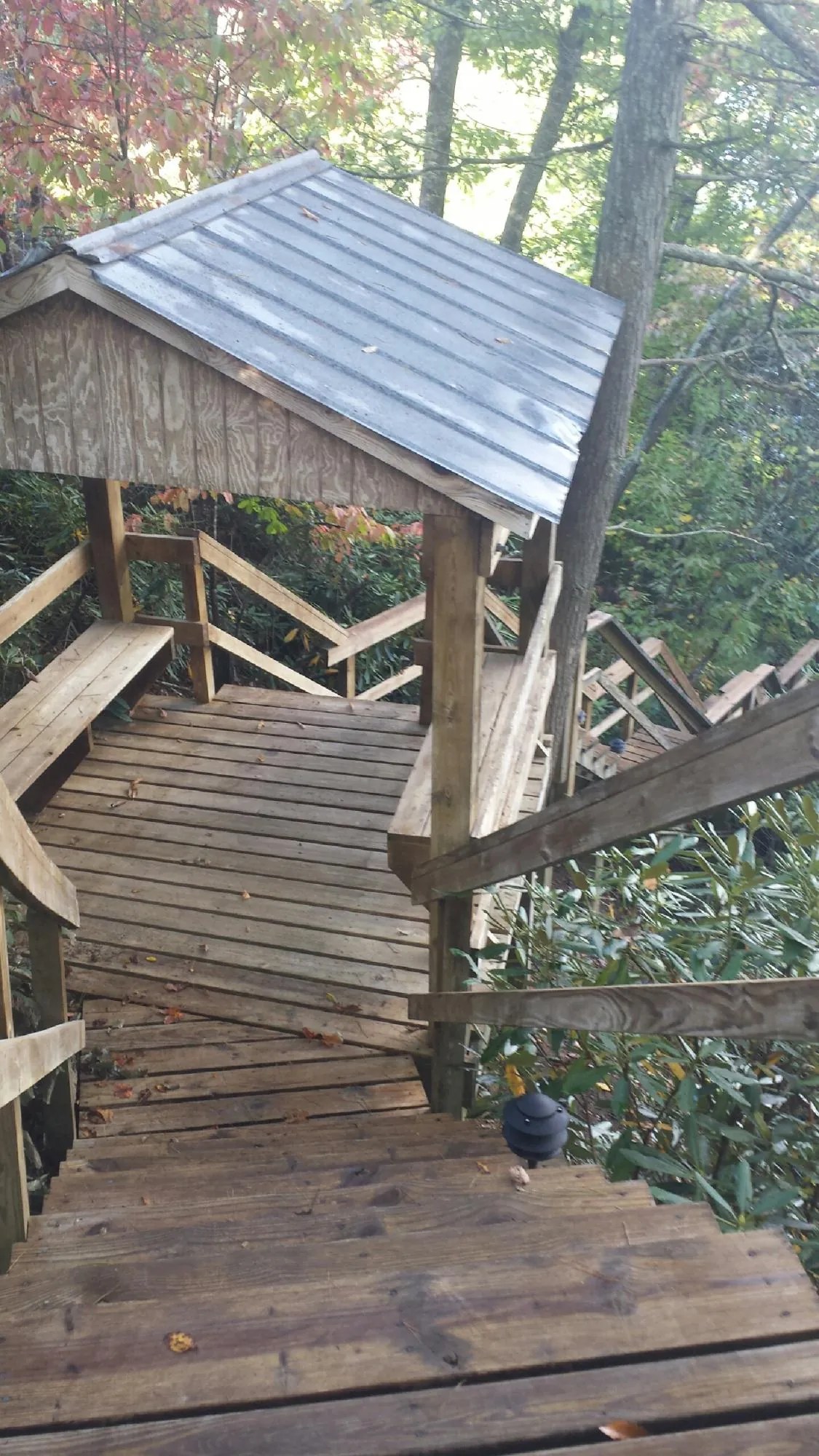 Metal roofed shelter over wooden steps on a wooded walkway — Skylight Repair & Installation work by our crew in Goodspring