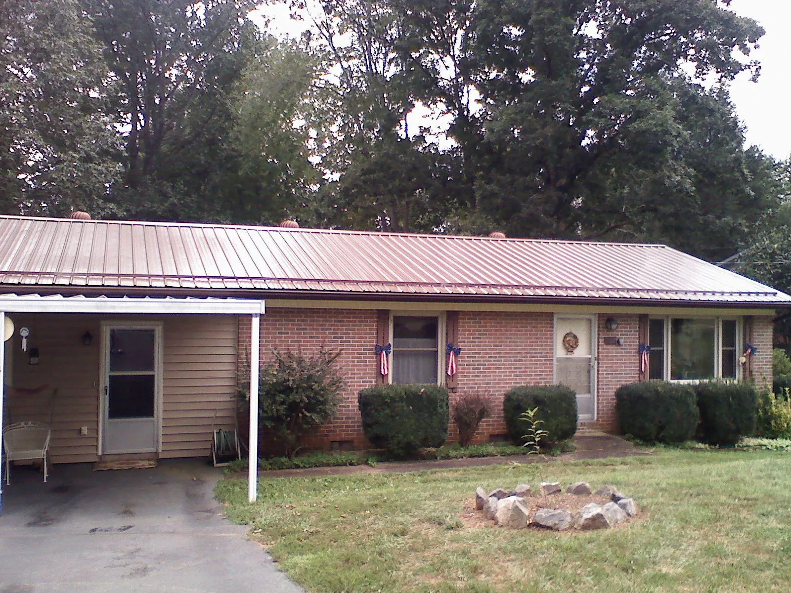 Bronze metal roof and carport on a brick ranch home — Roof Repair work by our crew in Goodspring