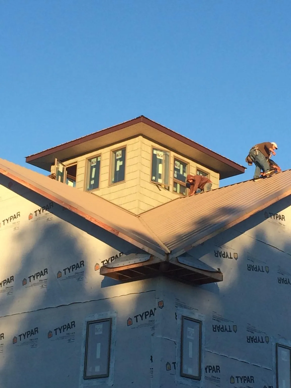Roofers working around a rooftop cupola on a new metal roof at sunset — Roof Waterproofing in Goodspring by Roofing Brothers